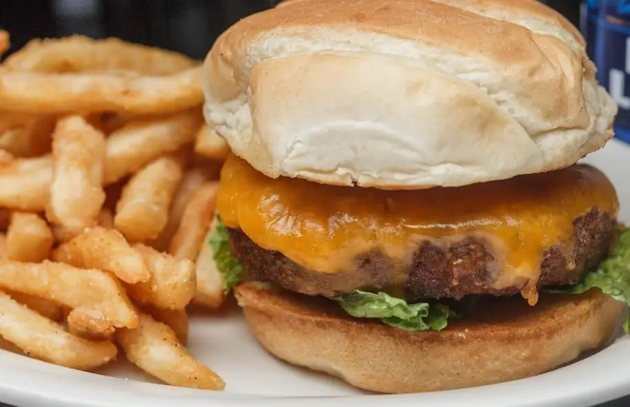 A cheeseburger on an onion bun with french fries