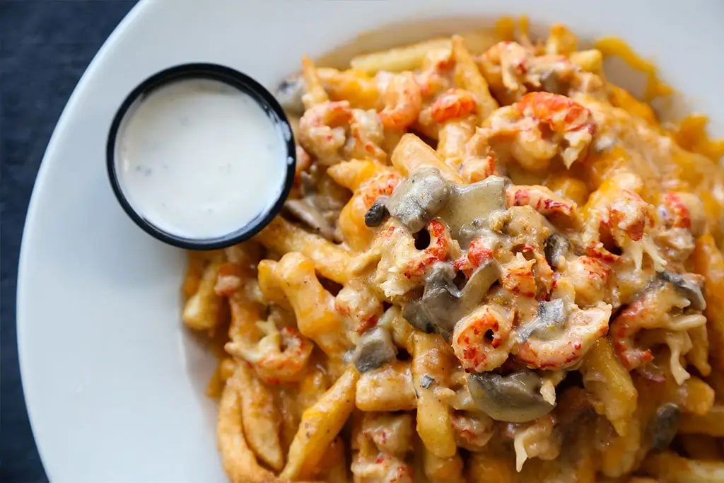 Cajun Hebert Fries topped with crawfish mushroom cream sauce and cheddar, with a side of ranch
