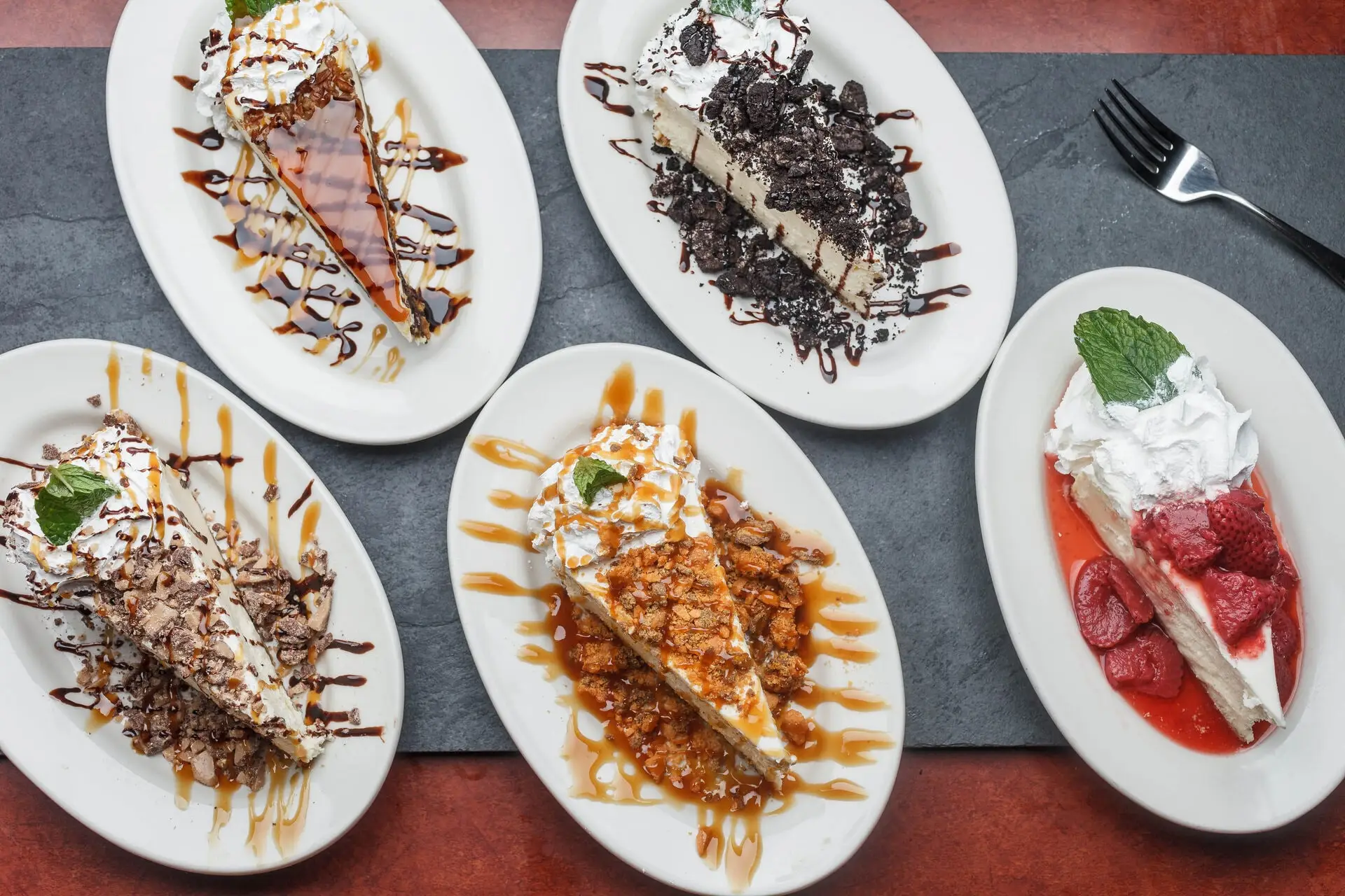 A table of New York-style cheesecakes: Oreo, turtle, toffee and strawberry