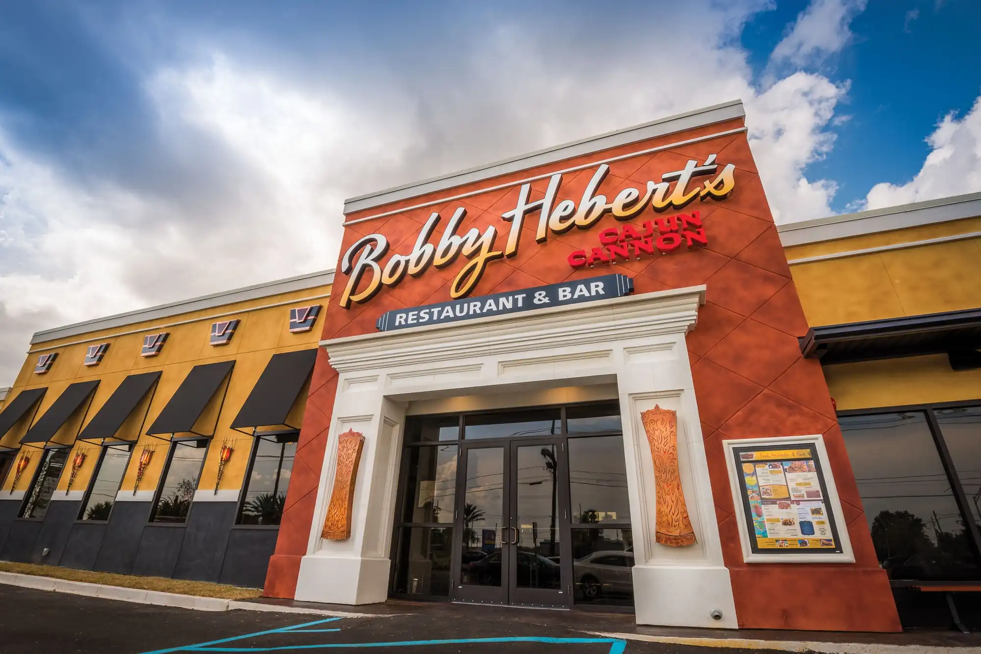 Bobby Hebert’s Cajun Cannon Restaurant & Bar on Veterans Memorial Boulevard in Metairie, its red-and-gold sign against a blue sky