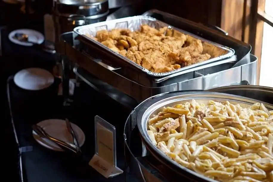 Catering trays of pasta and fried seafood in chafing dishes